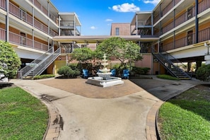 A courtyard with a central fountain, surrounded by multi-story buildings with balconies and staircases.