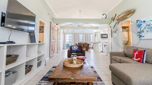 A spacious living room with a flat-screen TV, a wooden coffee table with a tray, and a sofa with decorative pillows. - Purple Pearl - (GVR06919) (Galveston)