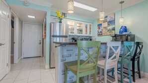 Una cocina moderna con una isla central, armarios blancos e iluminación colgante.
