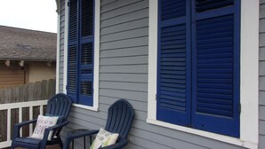A porch with two Adirondack chairs, each with a pillow.
