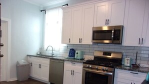 A modern kitchen with white cabinets, stainless steel appliances, and a granite countertop.