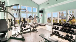 Une salle de sport bien équipée, avec des appareils de cardio, des poids libres et un banc de musculation.