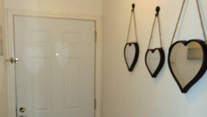 Un pasillo con una puerta blanca y tres adornos con forma de corazón.