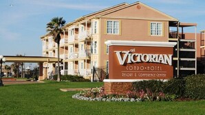 Hotel condominio Victoriano con un cartel, varios balcones y un césped bien cuidado.