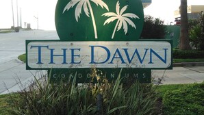 A sign for "The Dawn" with palm tree graphics. - Surf's Up at the Dawn BEACH FRONT (Galveston)