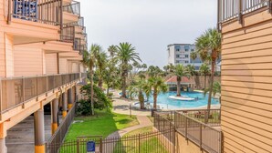Un hotel con zona de piscina, palmeras y un área de descanso techada.