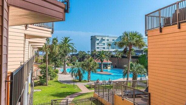 Un hotel con piscina, palmeras y vistas a un edificio de gran altura.
