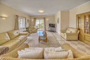 A spacious living room with beige sofas, a coffee table, and a television. - Casa Vista Cumeada - Peaceful Hillside Villa (Silves)