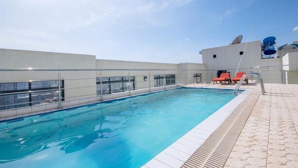 A rooftop swimming pool with clear blue water, surrounded by a white tiled deck and a glass railing. - Yohana Residences (Nairobi)
