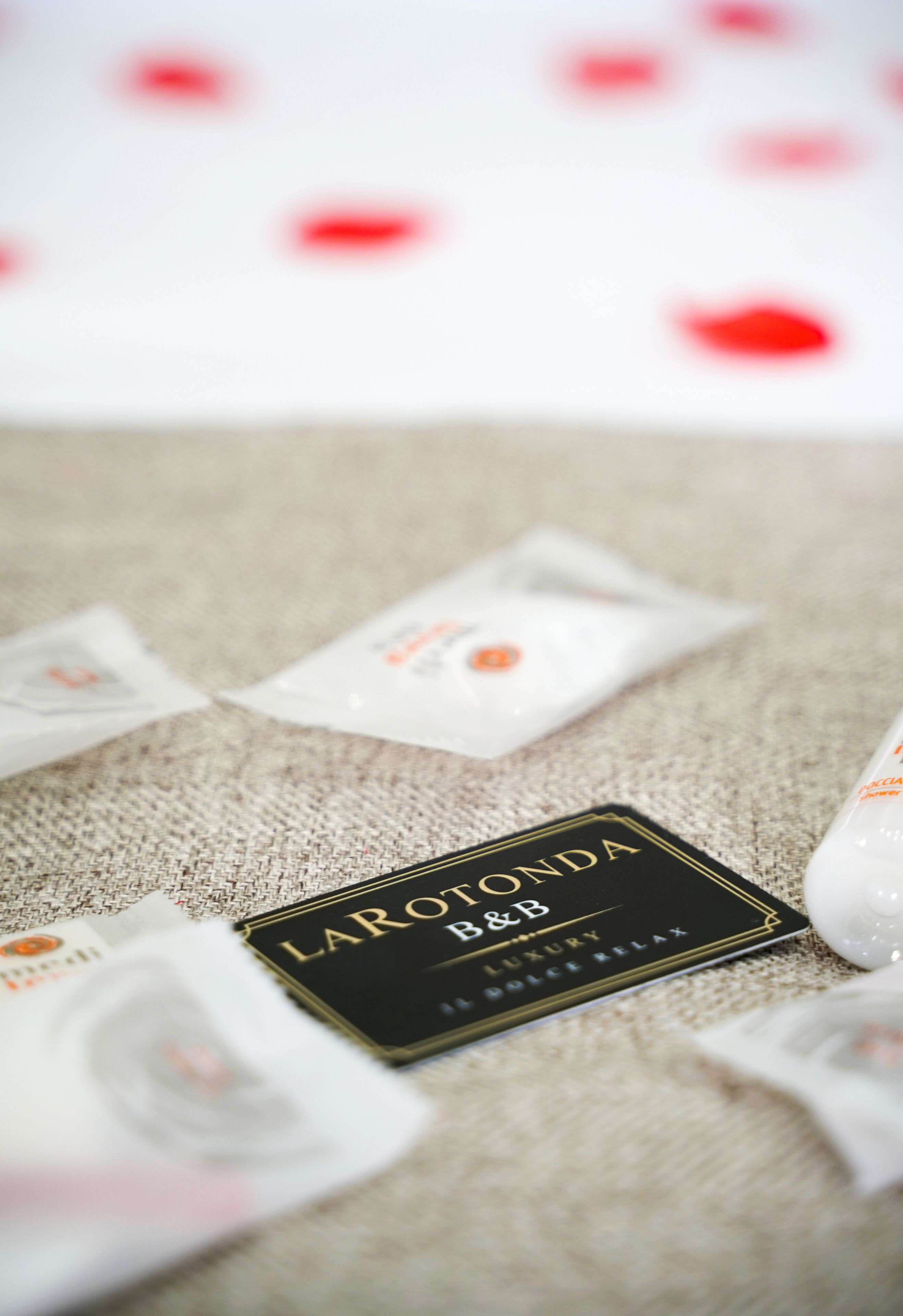Eine luxuriöse Hotelkarte mit dem Aufdruck "LAROLONDA B&B" und einem Schild "LUXURY POOL RELAX", umgeben von weißen Päckchen auf einem strukturierten Teppich.