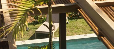 A pool area with wooden loungers and a palm tree.