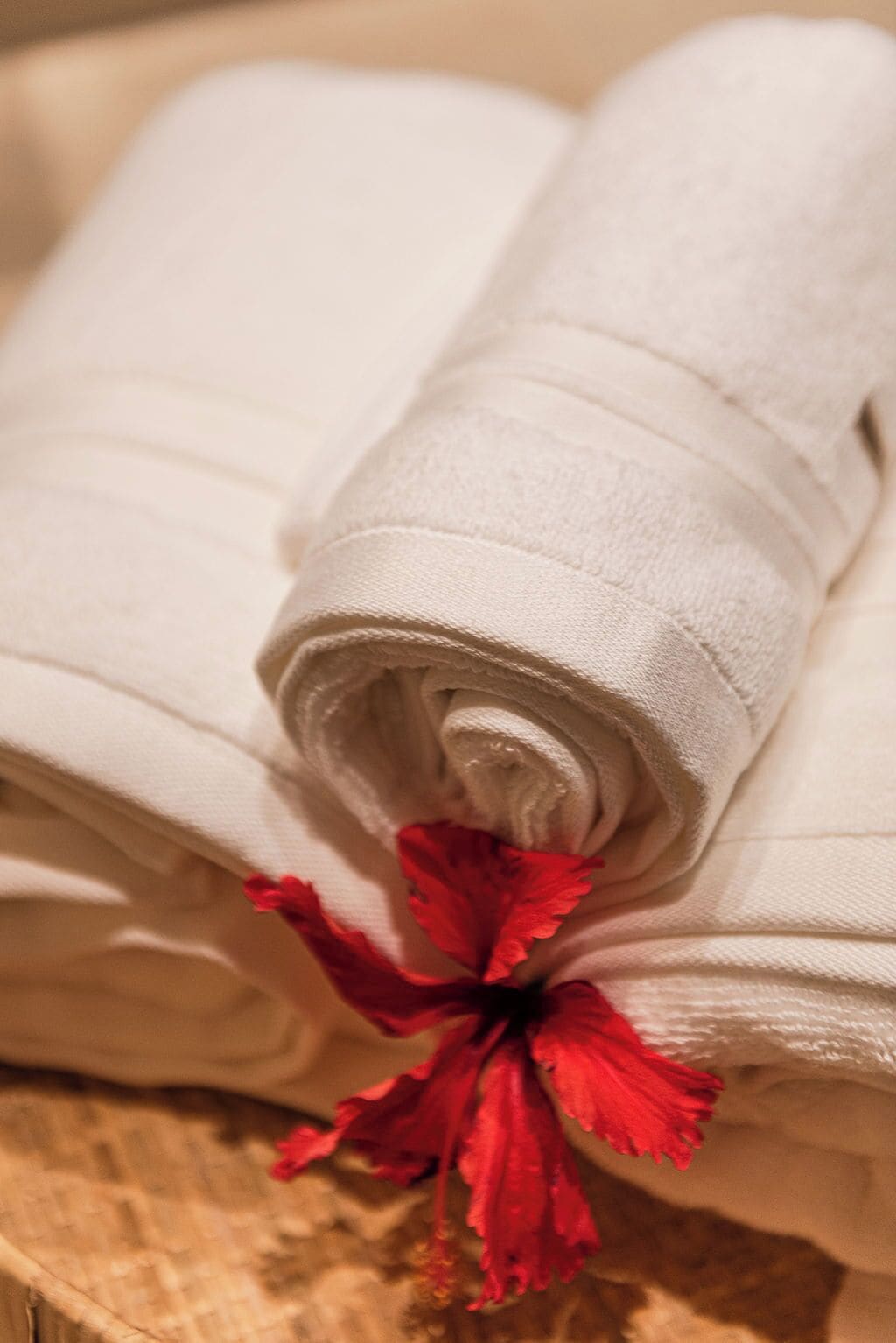 A stack of white towels with a red flower tied to one of them.