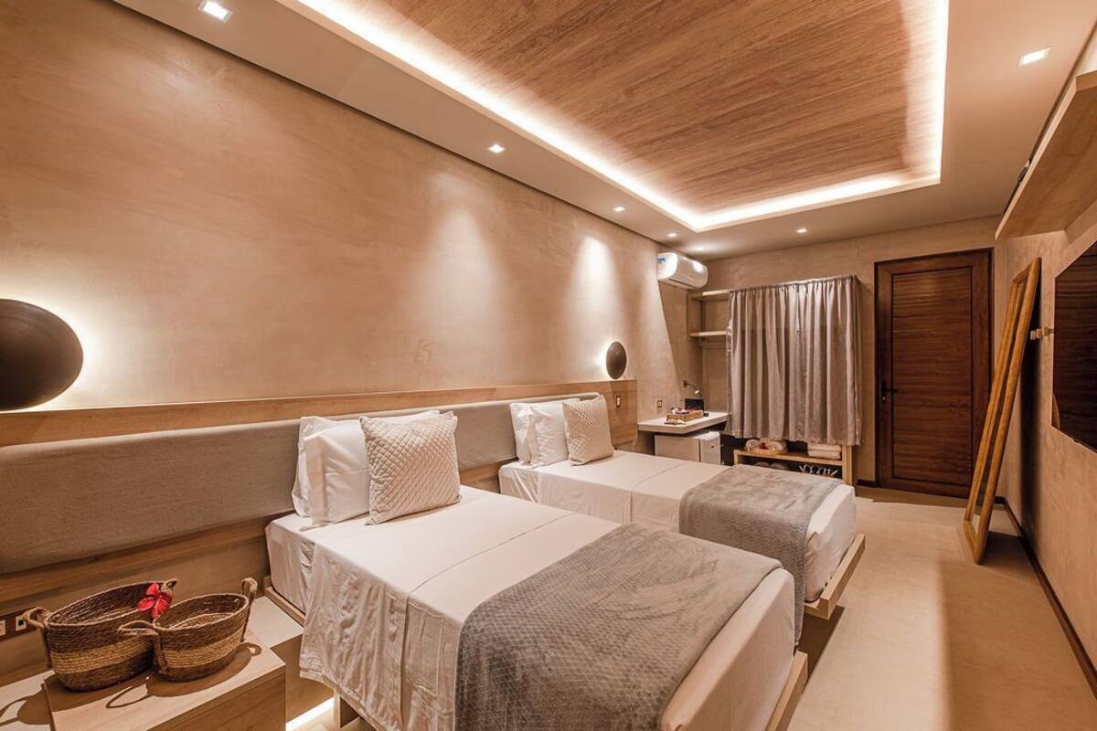 Ein Hotelzimmer mit zwei Betten, einem Nachttisch, einem Spiegel und einem Kleiderschrank.