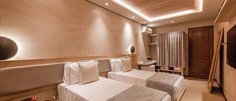 A hotel room with two beds, a bedside table, a mirror, and a wardrobe.