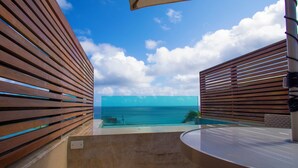 A balcony with wooden slats, a glass table, and a view of the ocean. - POUSADA DO MIRANTE (Fernando de Noronha)