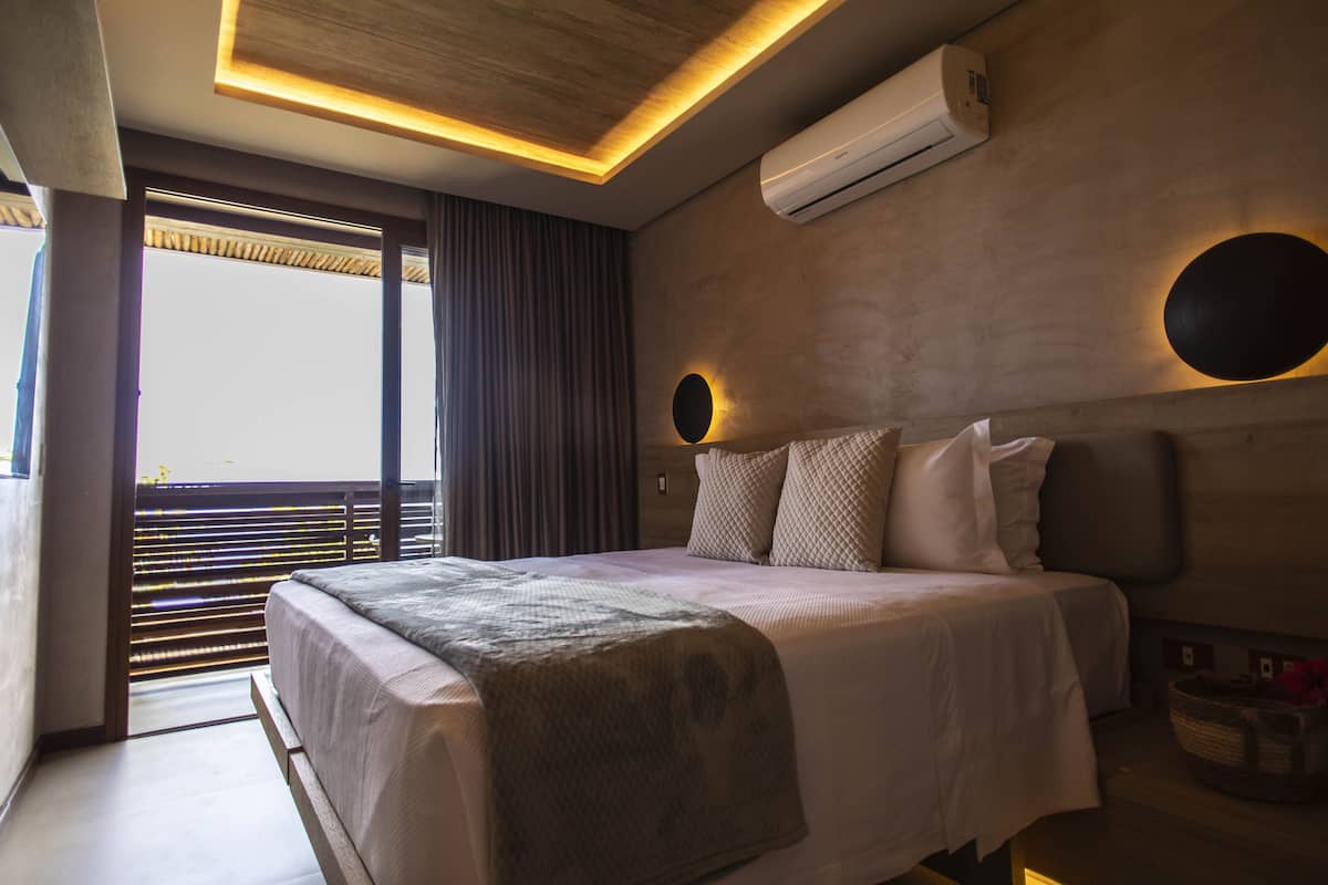 Ein modernes Hotelzimmer mit einem großen Bett, Blick durch das Fenster und einer Wand-Klimaanlage.