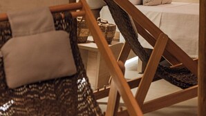 A modern hotel room with a wooden bed frame, a wooden chair, and a small table with a lamp. - POUSADA DO MIRANTE (Fernando de Noronha)