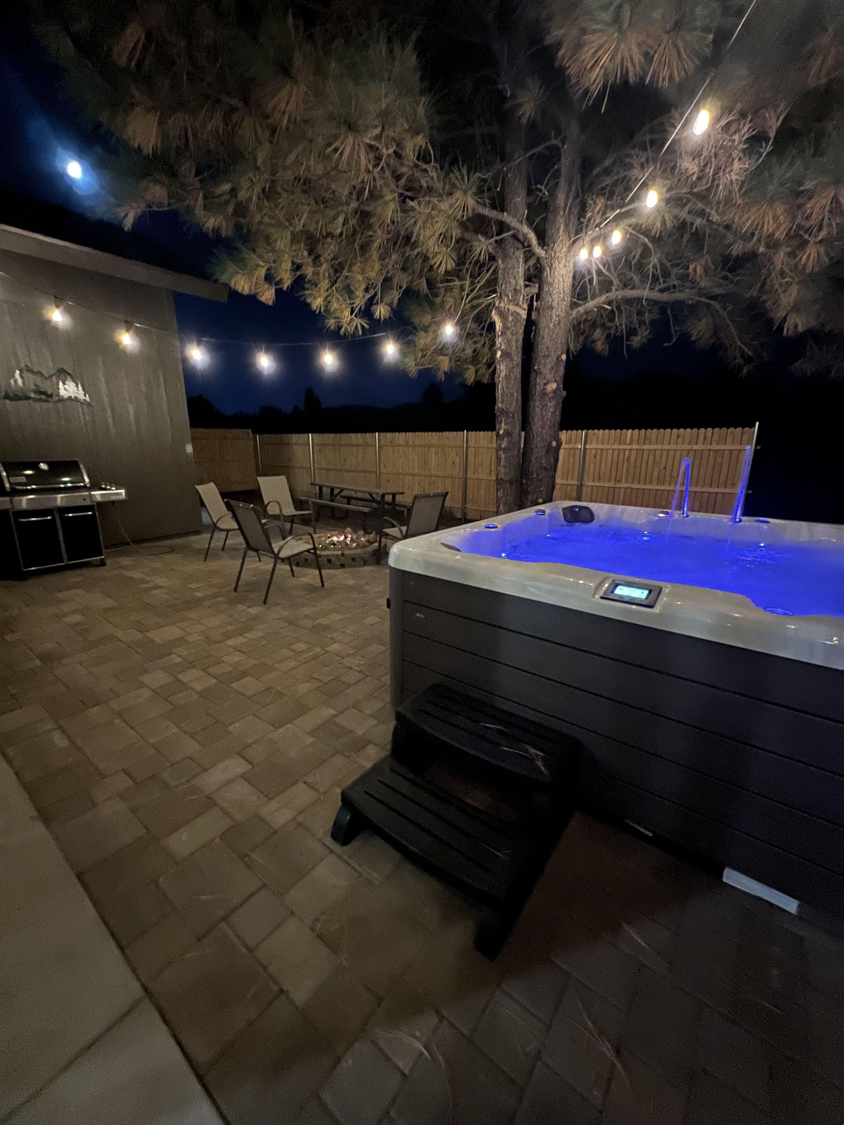 An outdoor patio area with a hot tub, a barbecue grill, and outdoor seating.