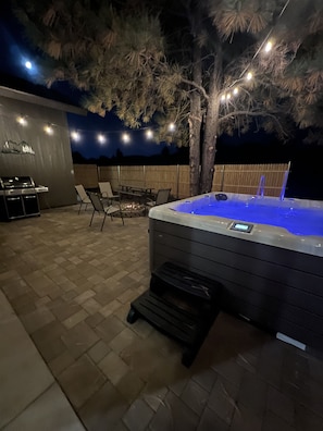 An outdoor patio area with a hot tub, a barbecue grill, and outdoor seating. -     ⭐ Grand Canyon Getaway - New Home - Golf Views Family Friendly Close to Town (Williams)