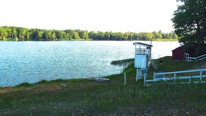 Um lago com um cais, uma torre de salva-vidas e um celeiro vermelho.