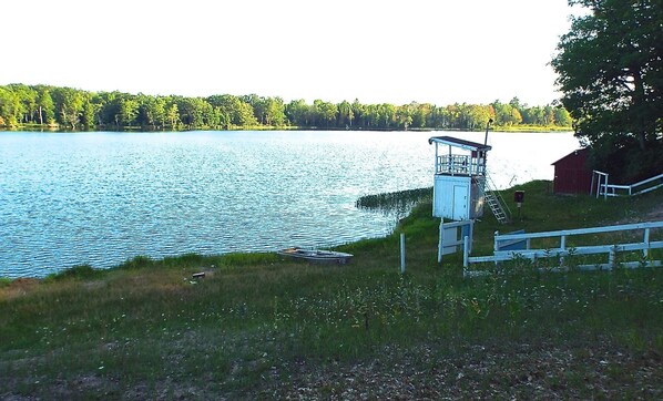 Un lac avec un quai, une tour de surveillance pour les sauveteurs et une grange rouge.