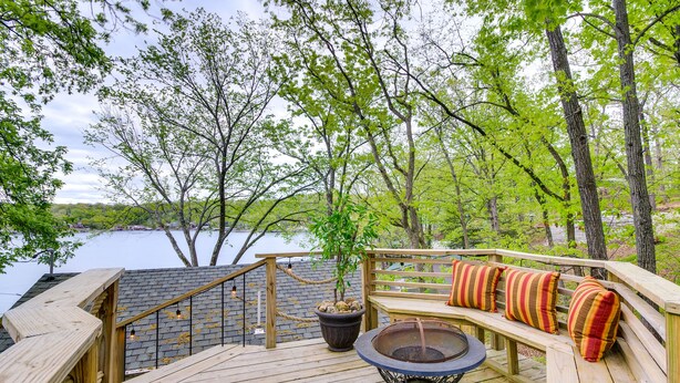 A wooden deck with a fire pit and seating area overlooking a lake.