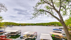 A lakeside dock with several boats, a covered seating area, and a tree in the foreground.