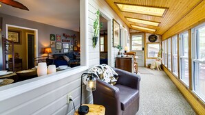 A cozy interior with a wooden ceiling, a sofa, a dining area, and a dog.