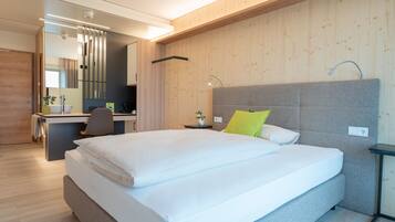 A modern hotel room with a large bed, a desk, and a chair.