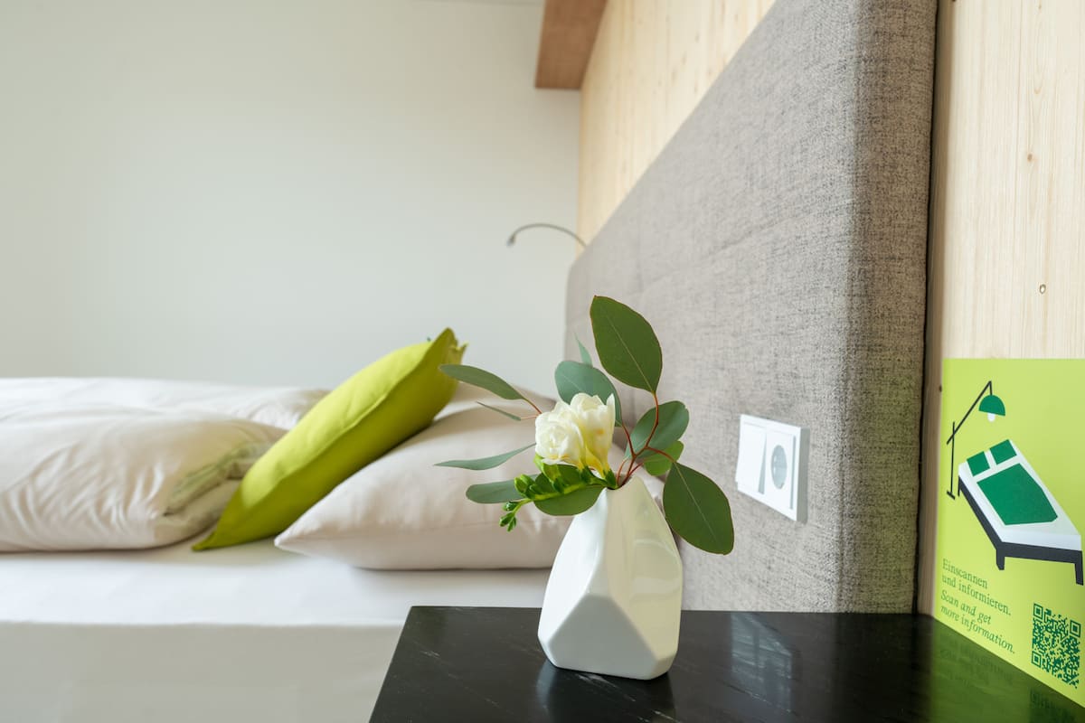Un vase blanc avec une fleur, posé sur une table noire dans une chambre d’hôtel.