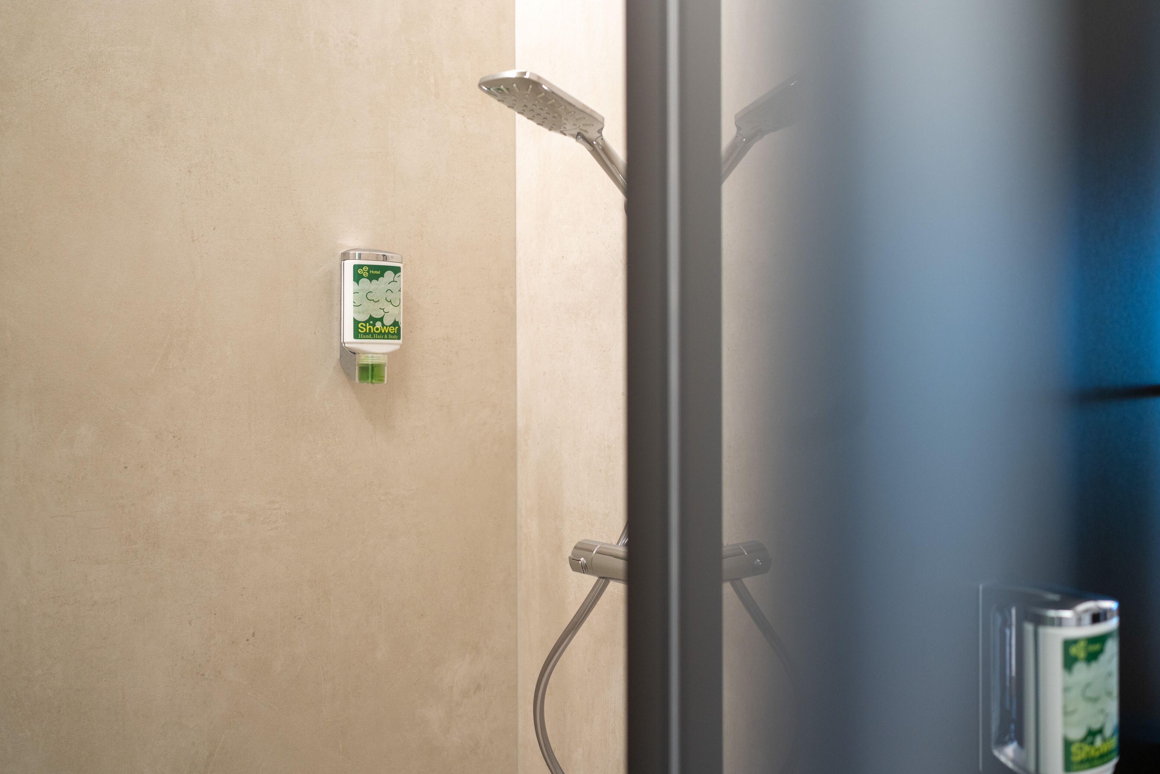 A shower area with a handheld showerhead and a wall-mounted control panel.