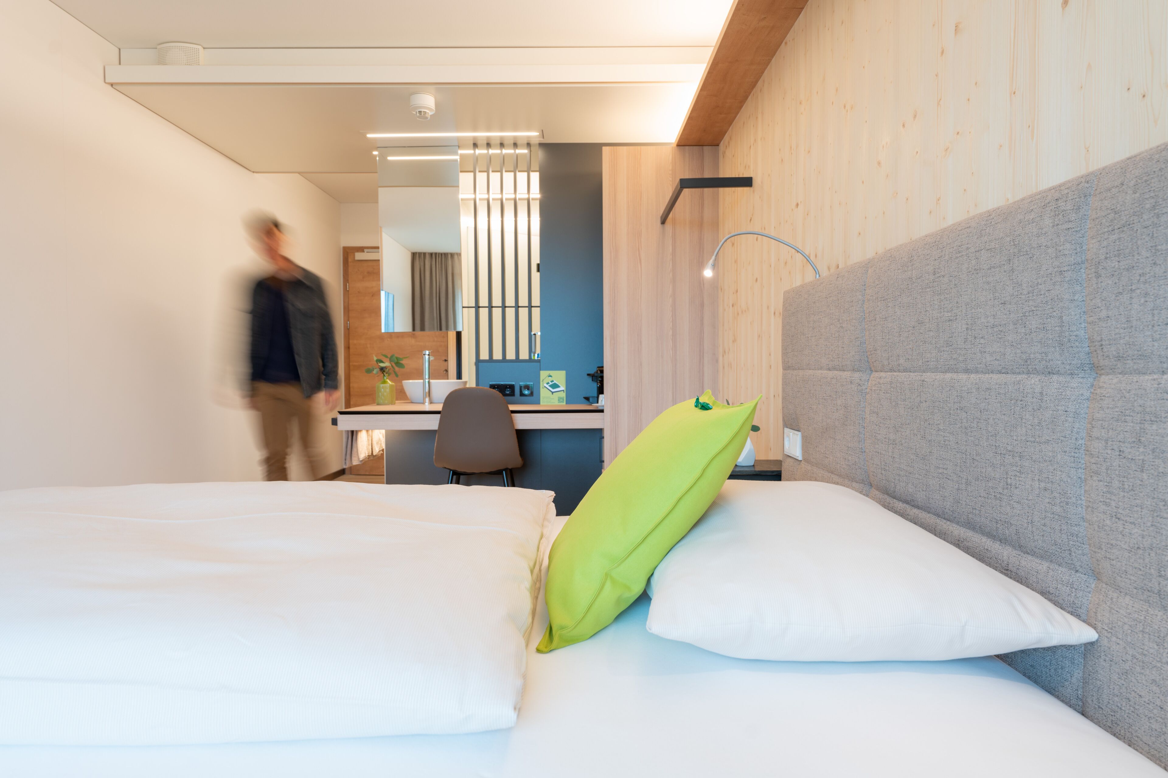 Quarto de hotel moderno com cama, escrivaninha e banheiro.