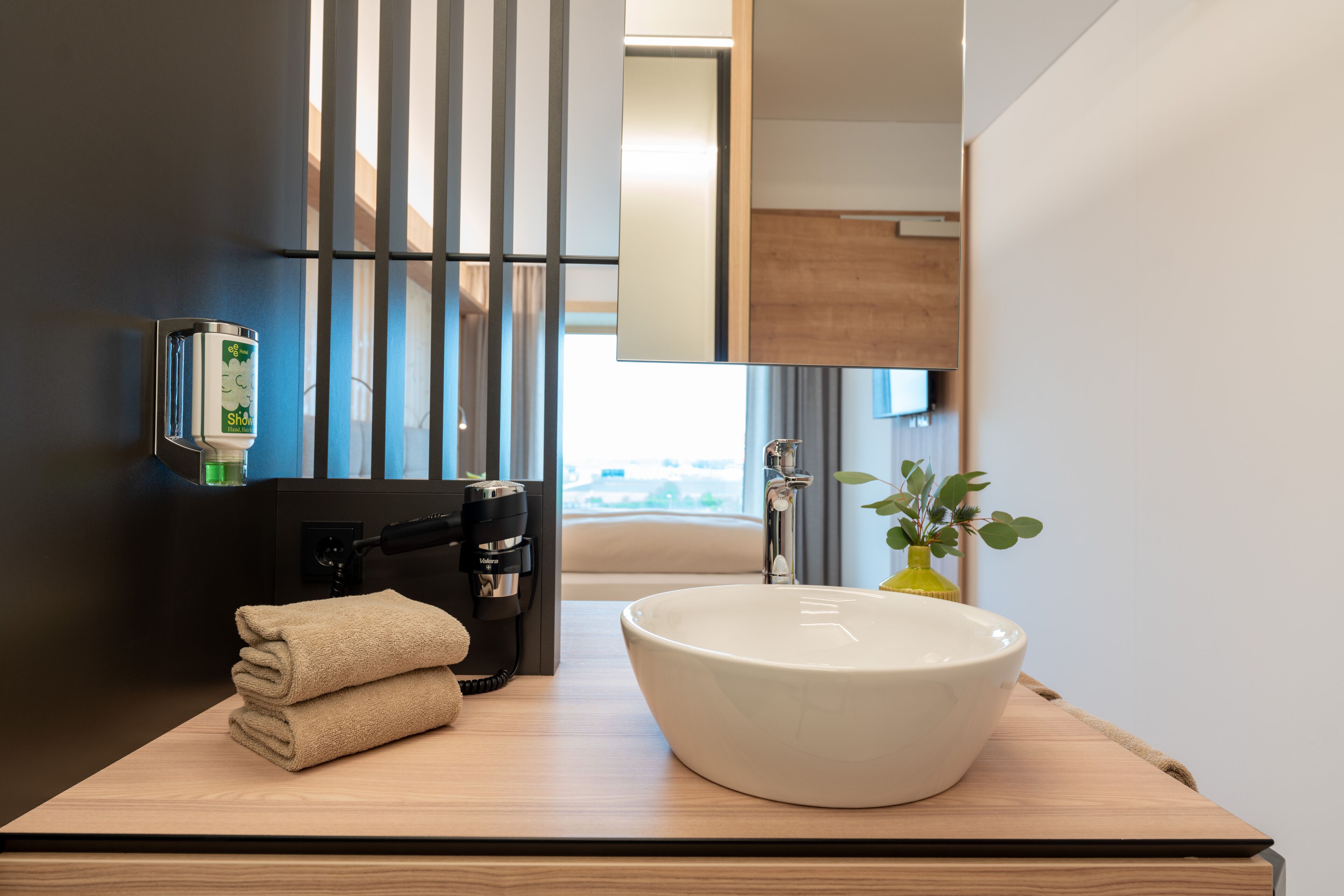 Uma casa de banho moderna com uma grande lavatório branco, um dispensador de toalhas e um espelho.