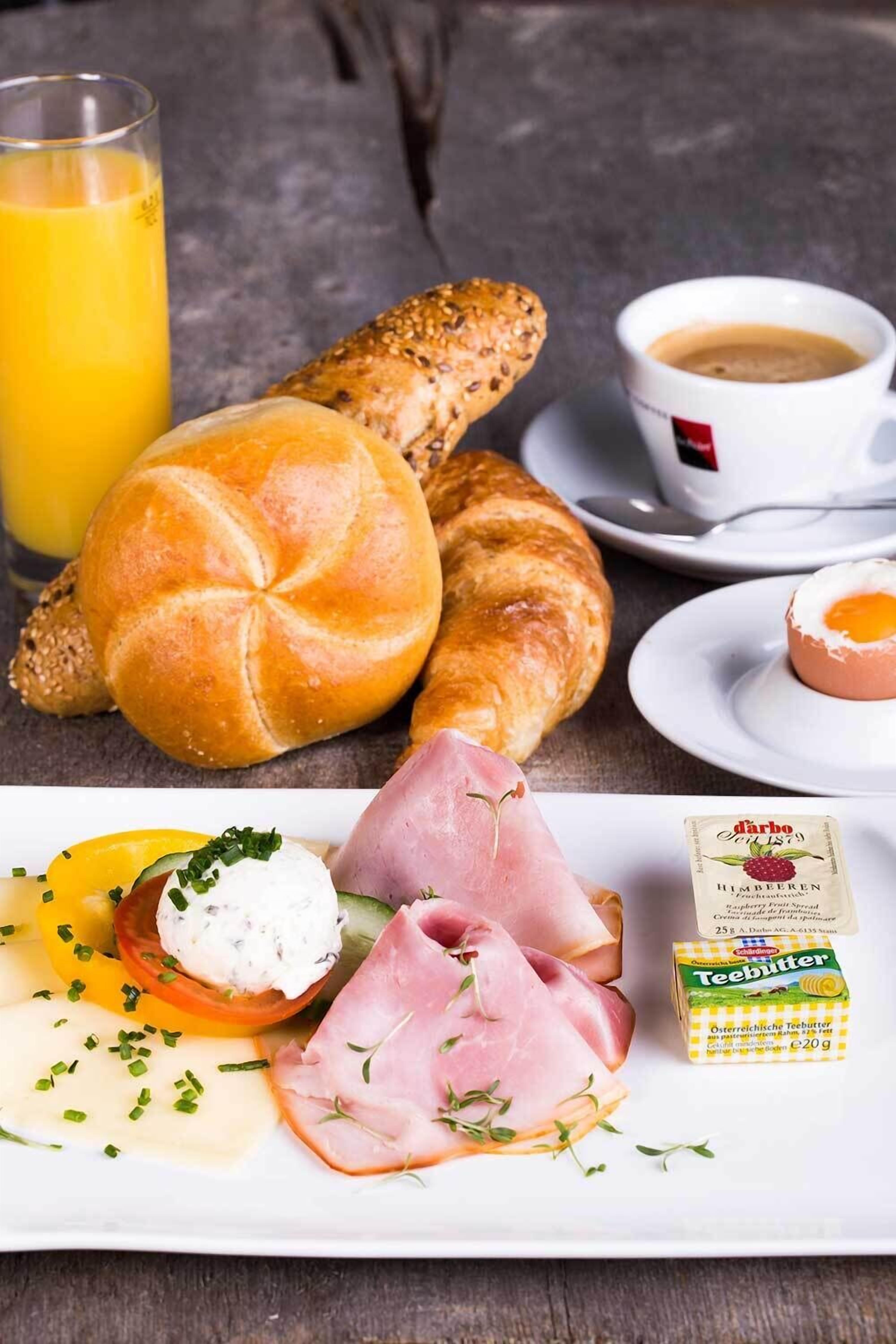 Un desayuno con pan, jamón, queso y una taza de café.