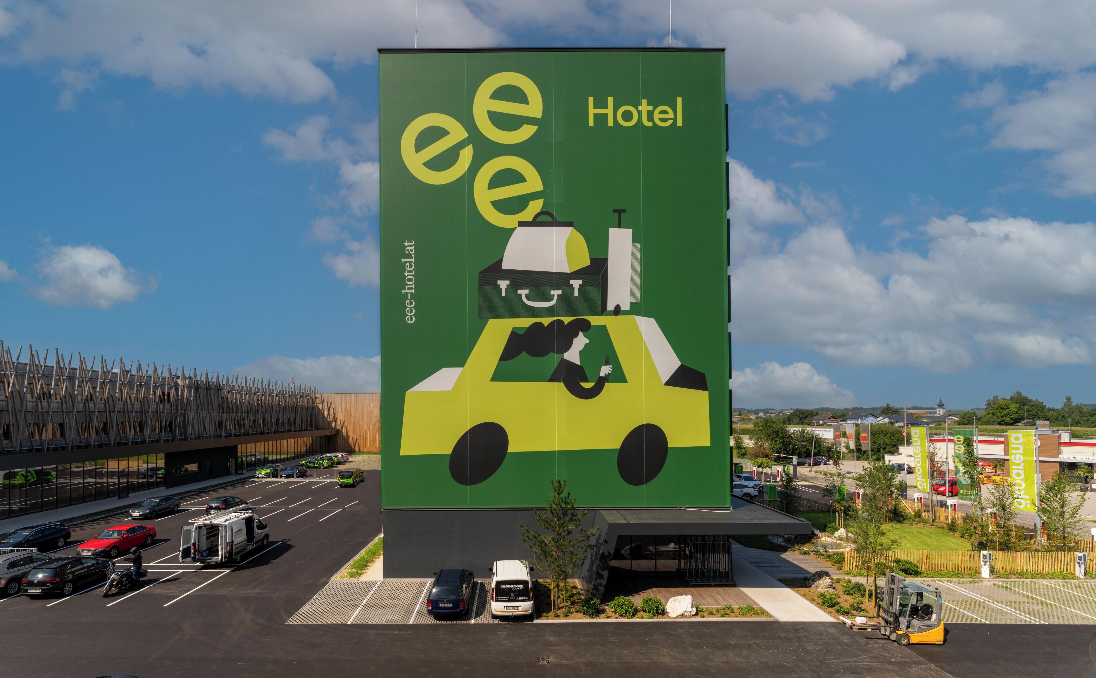 A large billboard advertising a hotel with a cartoon character driving a taxi.