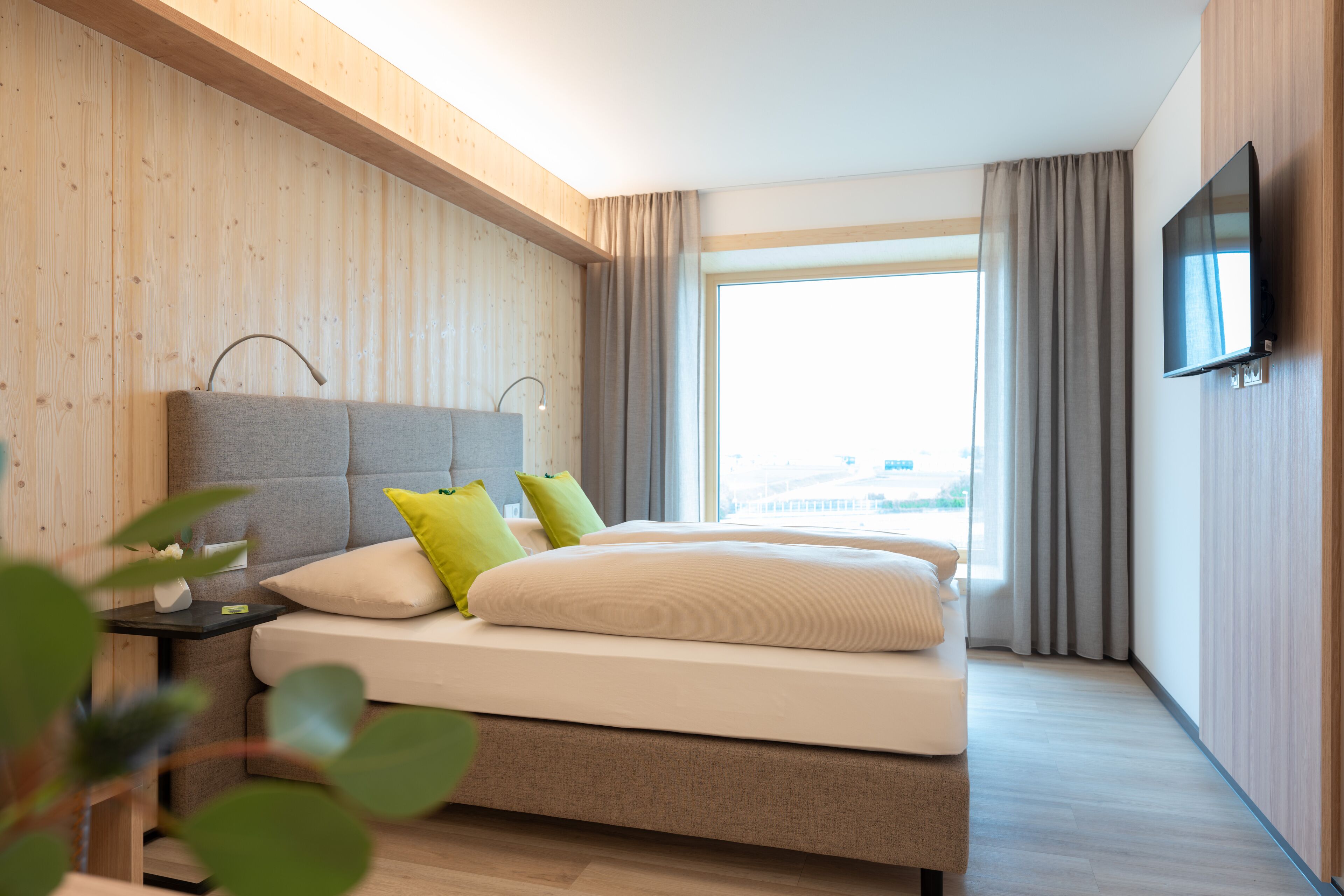 Una habitación de hotel moderna con una cama grande, una televisión de pantalla plana y vistas a la ciudad.