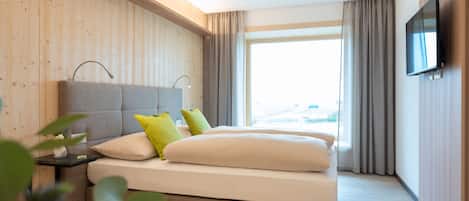 Una habitación de hotel moderna con una cama grande, una televisión de pantalla plana y vistas a la ciudad.
