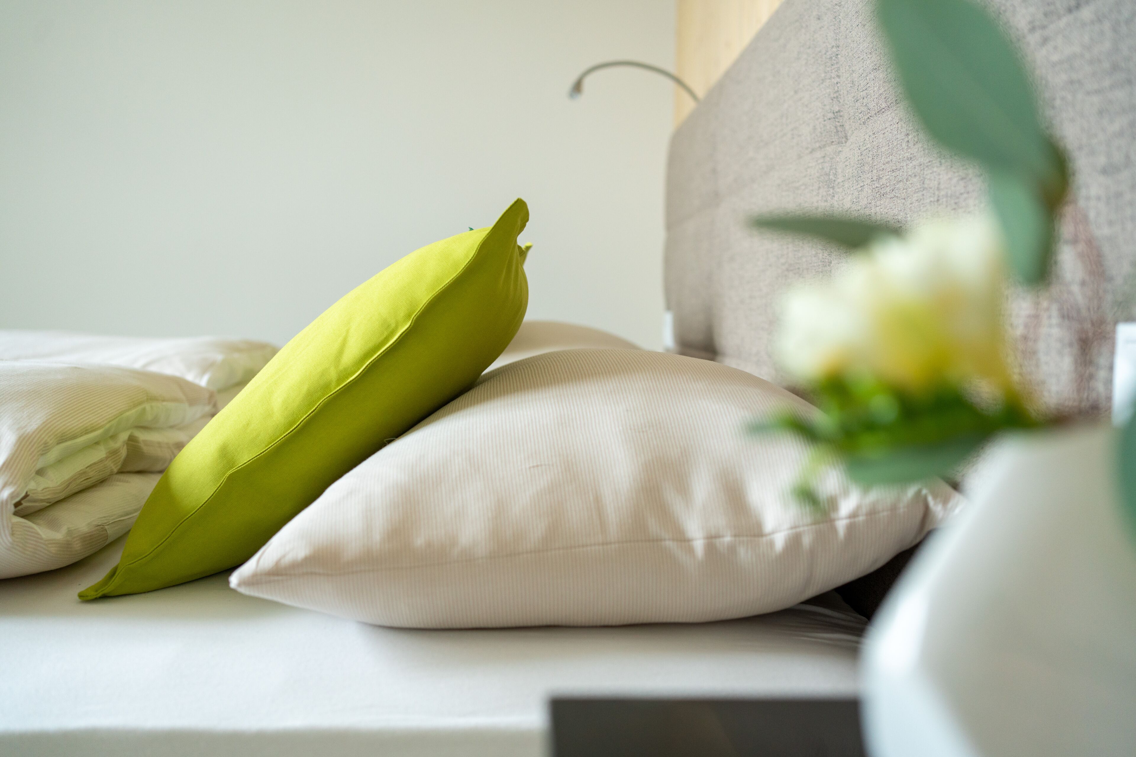 Ein Bett mit Kissen und einer Blumenvase.