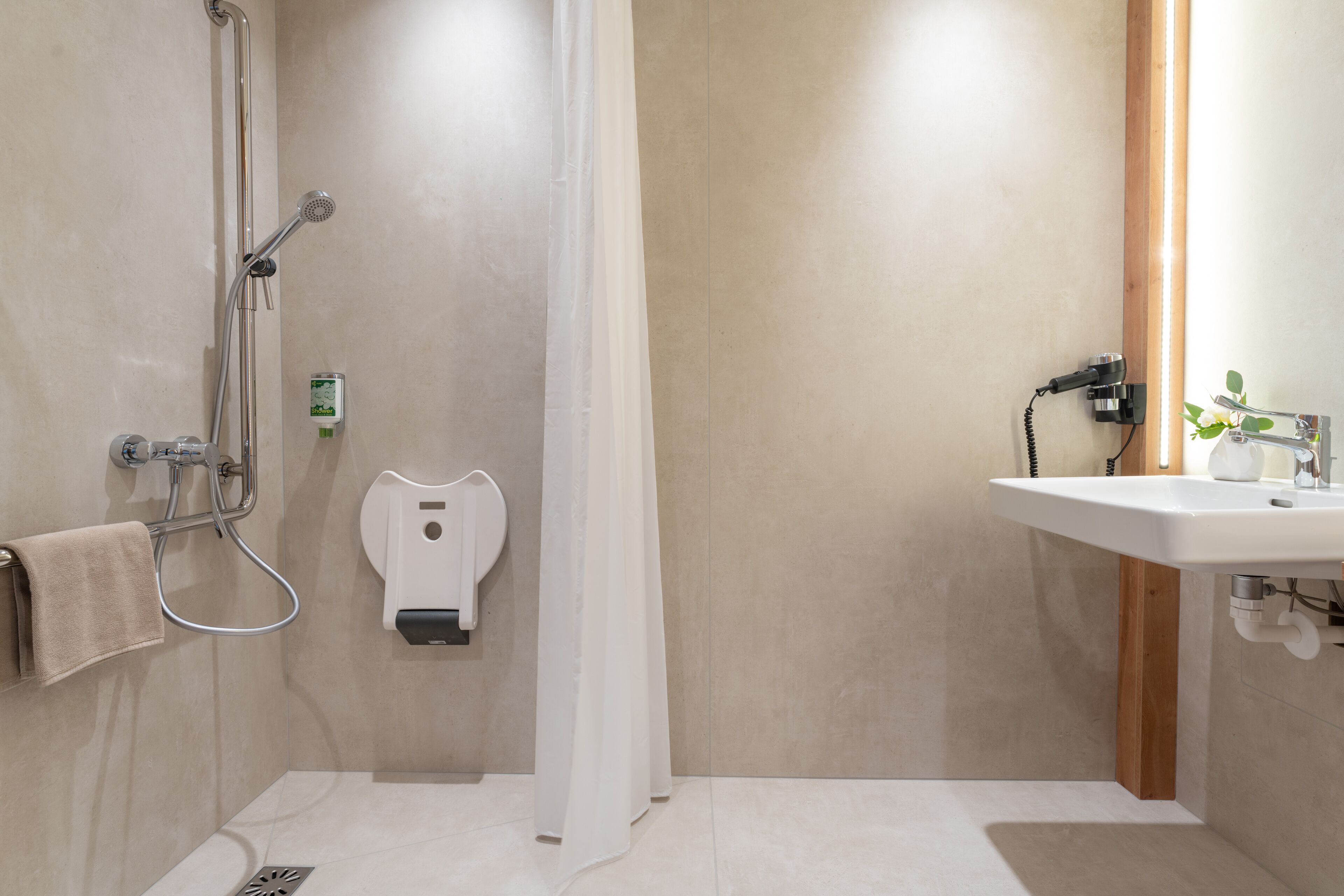 A modern bathroom with a shower, a towel rack, a soap dispenser, and a sink.