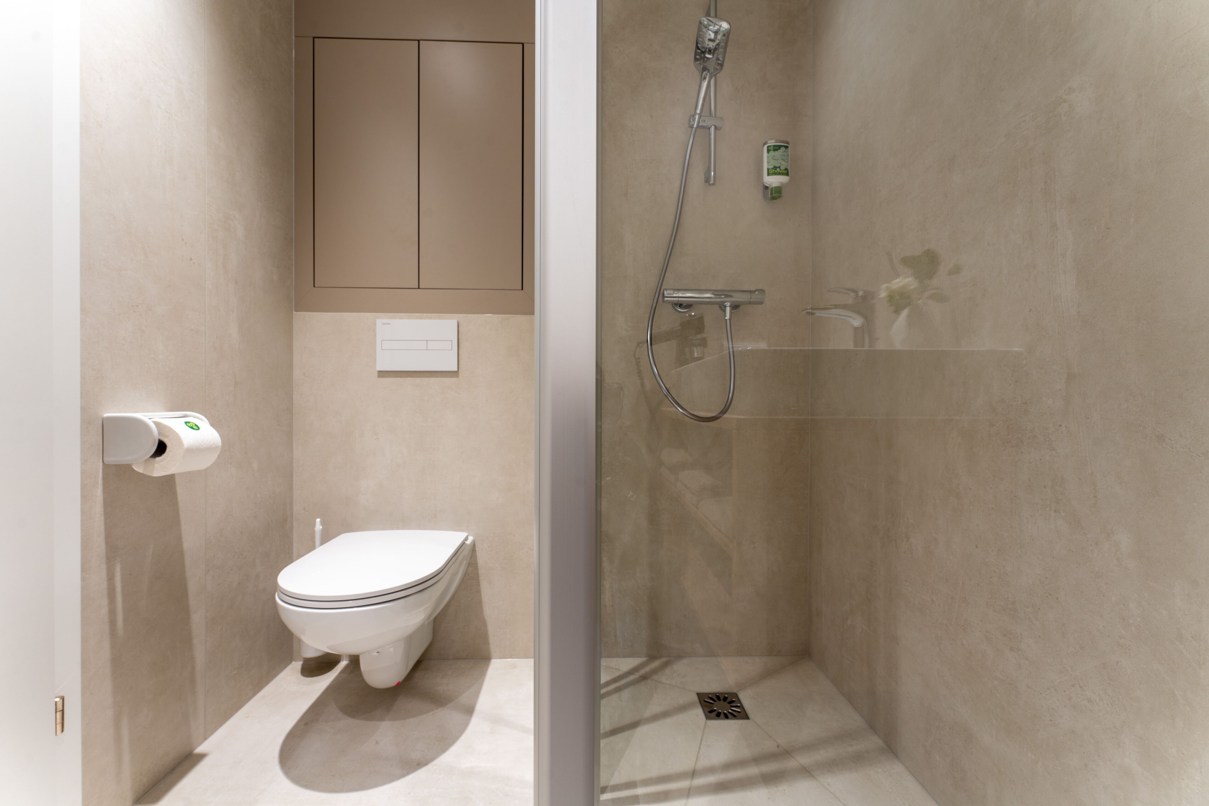 Un baño moderno con inodoro, ducha y cabina de ducha con paredes de vidrio.
