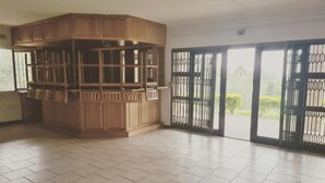 A spacious room with a large wooden cabinet, tiled flooring, and a view through a metal gate. - Leading Guest Farm  (Margate)