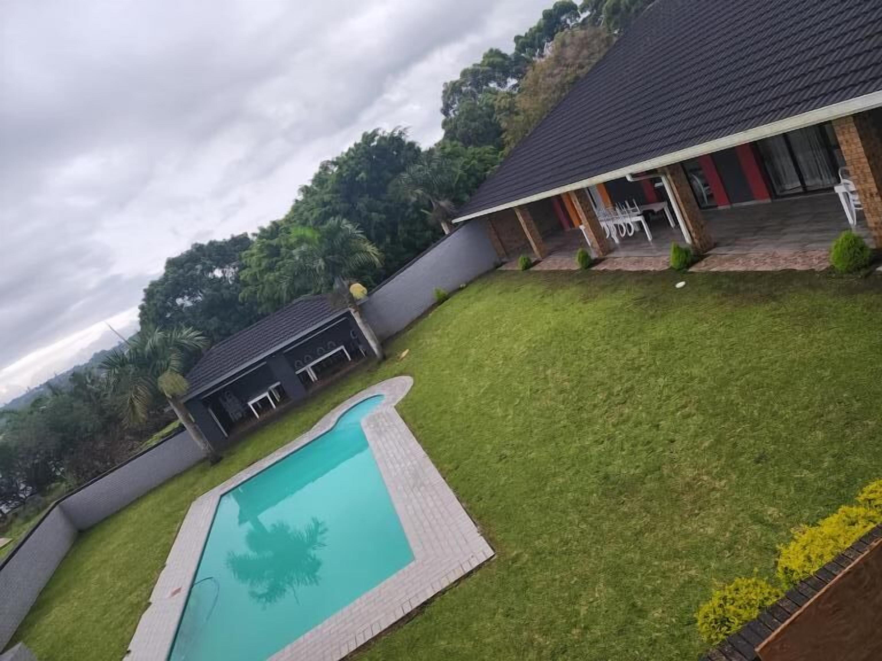 Una proprietà residenziale con piscina, patio coperto e vista su un paesaggio collinare.