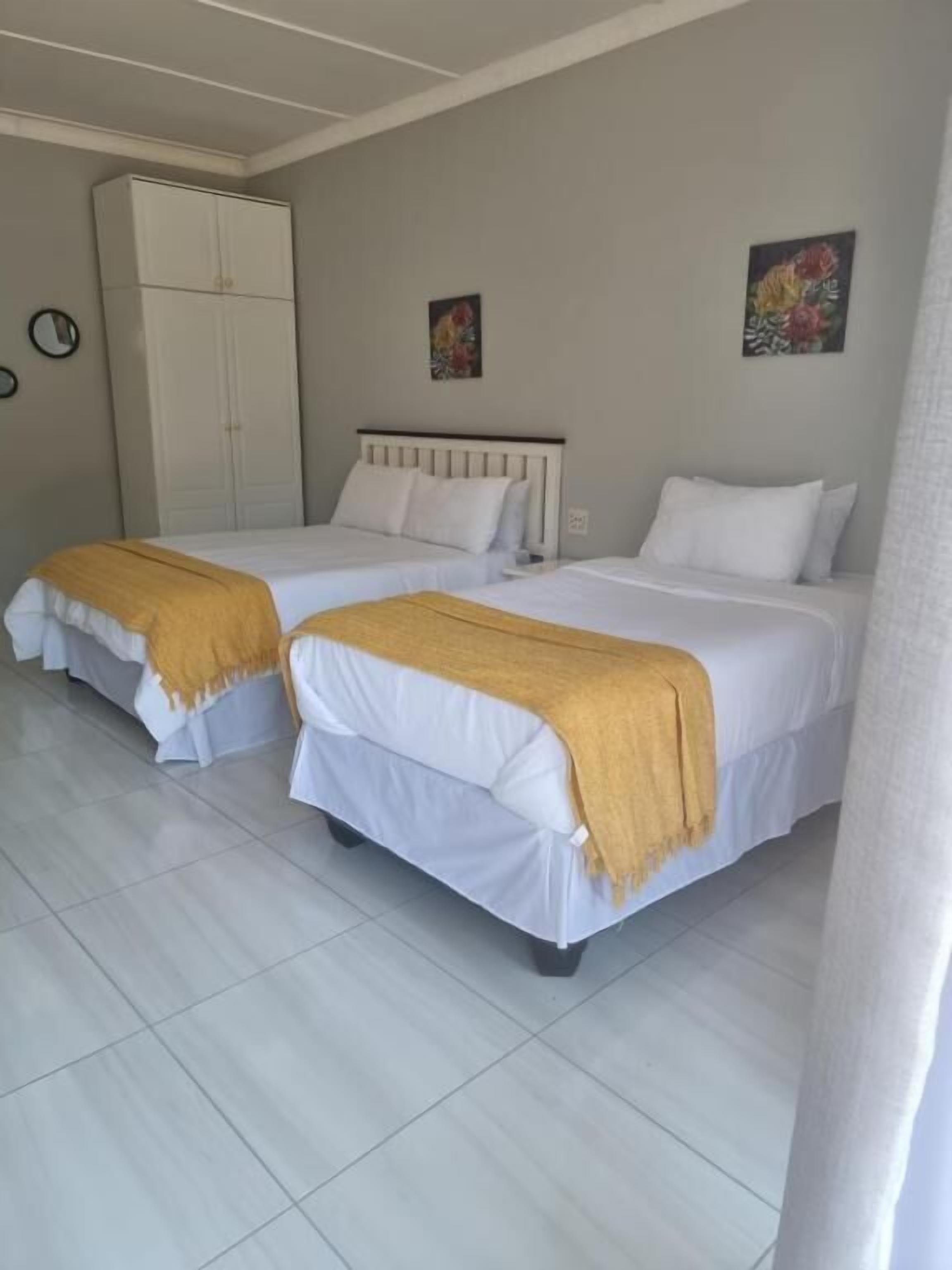 Una habitación de hotel con dos camas individuales, un armario y dos cuadros colgados en la pared.