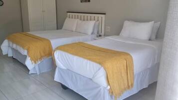 Una habitación de hotel con dos camas individuales, un armario y dos cuadros colgados en la pared.
