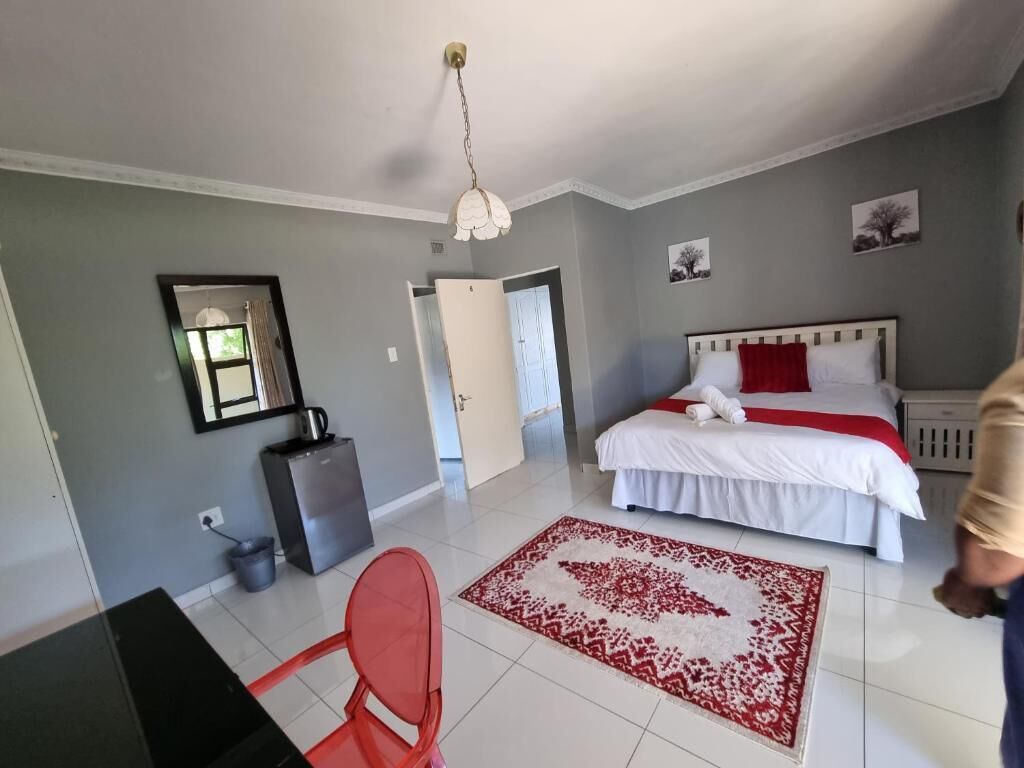A bedroom with a bed, a desk, and a chair.