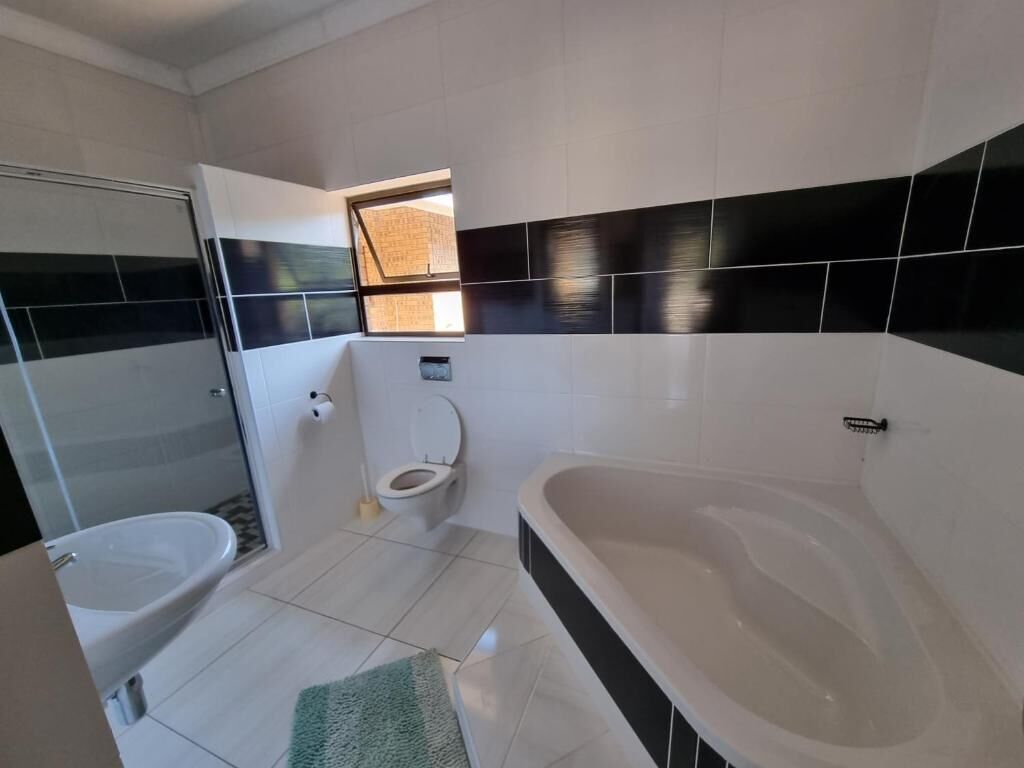 Et moderne badeværelse med badekar, toilet og bruseniche.