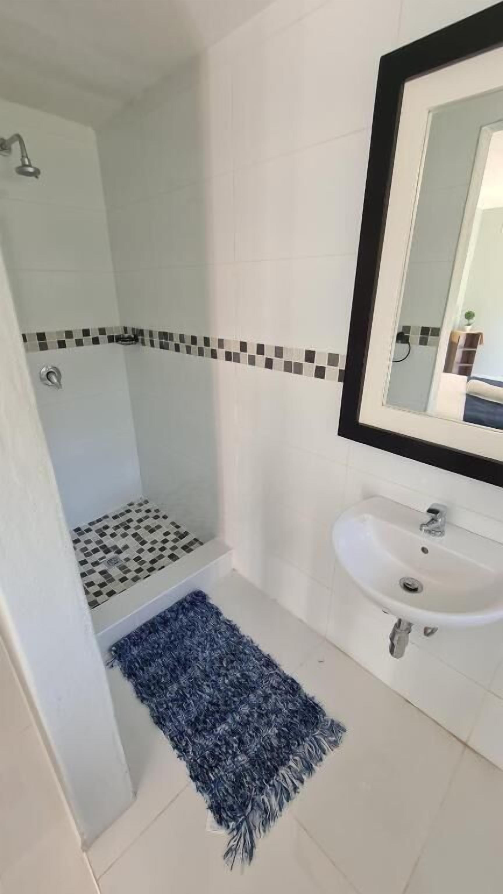 Un baño con ducha, lavabo y espejo.