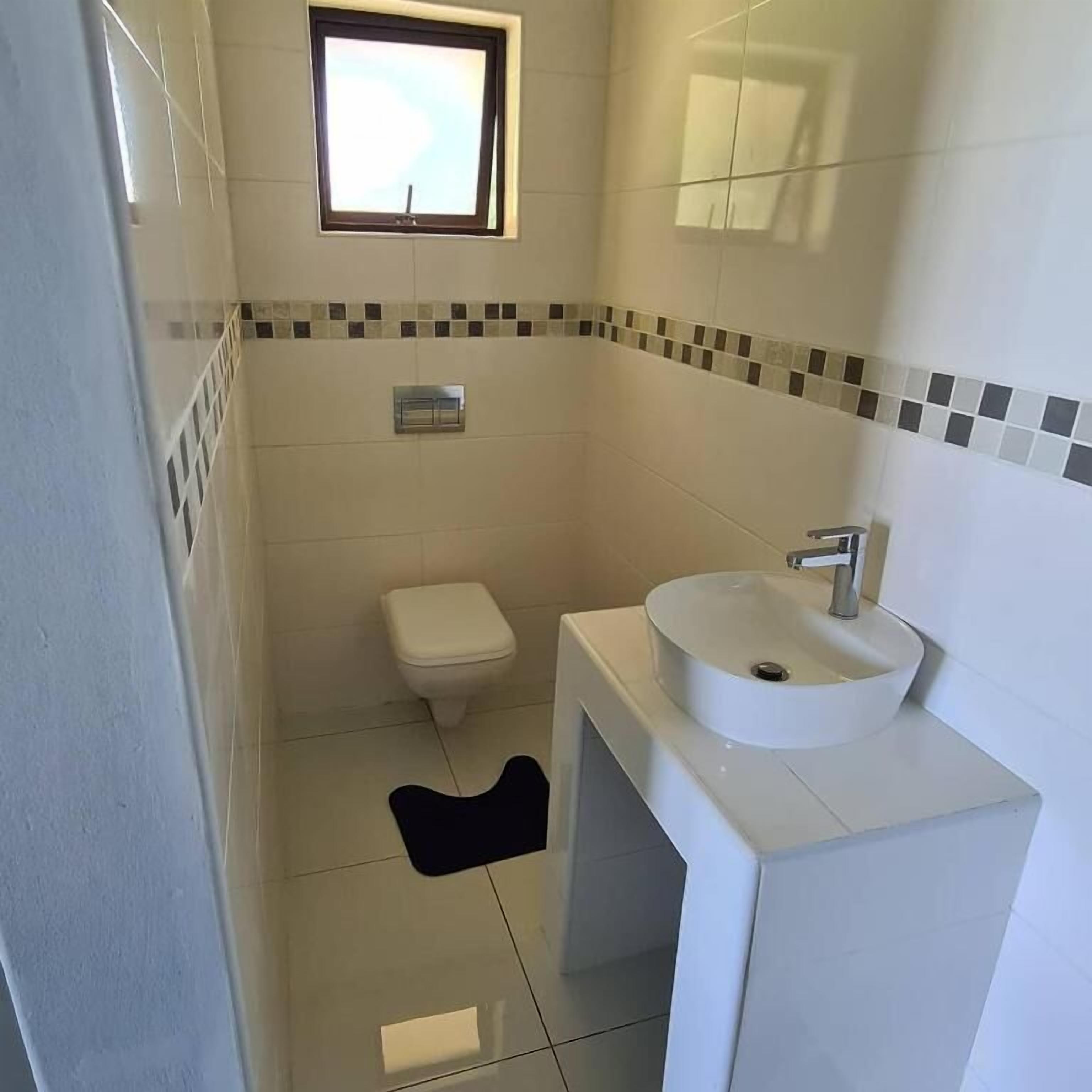 A small bathroom with a toilet, a sink, and a window.