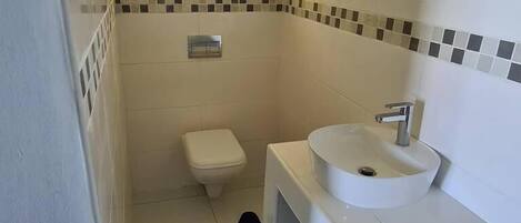 A small bathroom with a toilet, a sink, and a window.