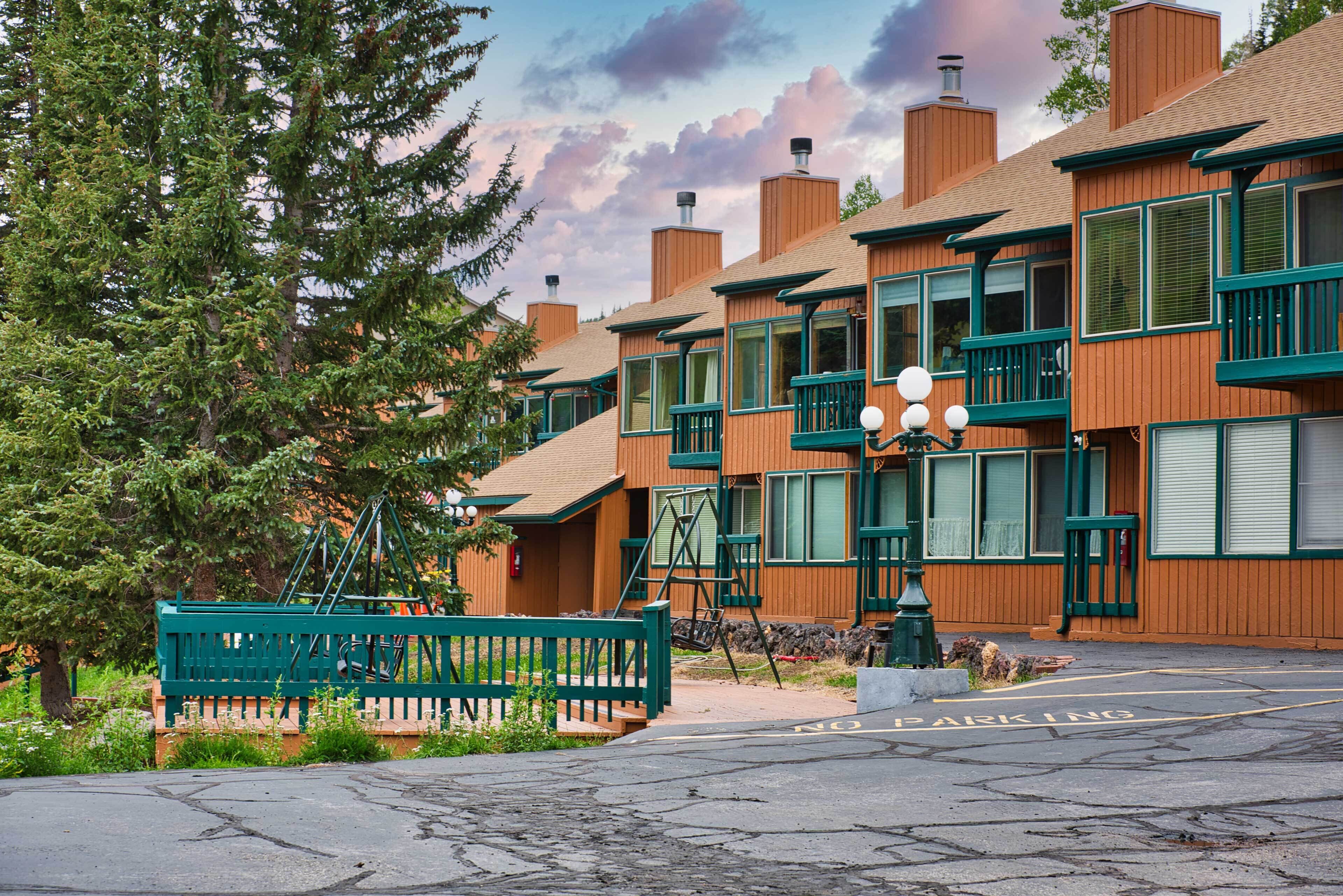 A row of wooden buildings with green accents, a bench, and a 'No Parking' sign.